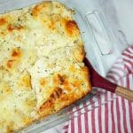chicken alfredo bubble up baked in a glass pan with red spoon.