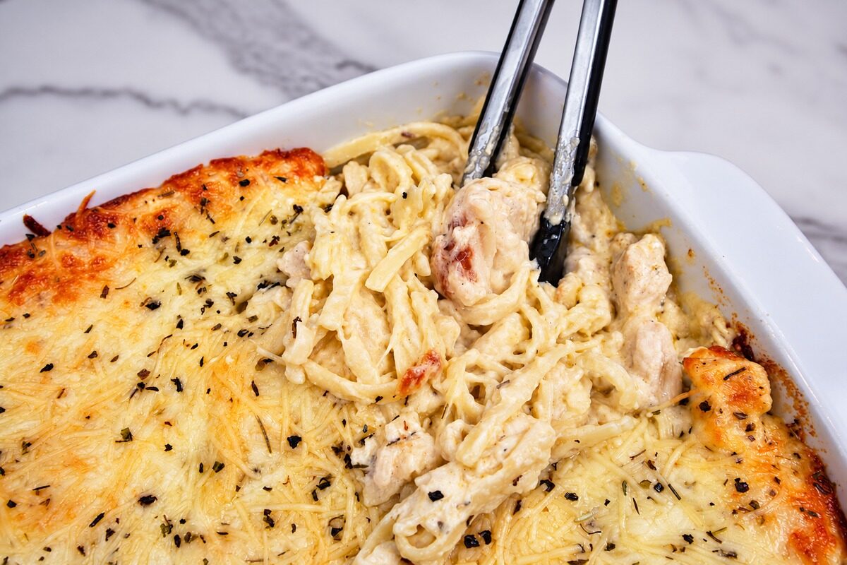 Chicken Tetrazzini served with tongs.