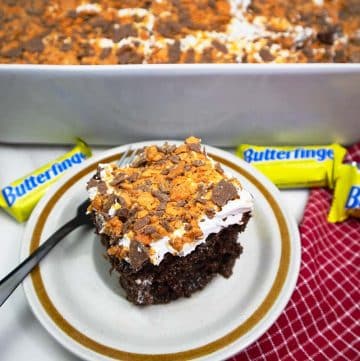 Butterfinger Poke Cake slice on a tan plate.