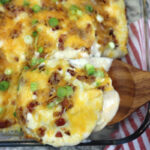 pierogi casserole served in a glass baking dish from a wooden spatula.