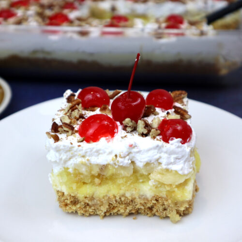 banana split cake slice on a white plate.