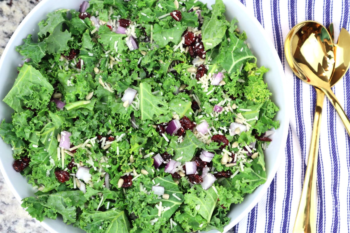Kale salad ingredients in a large white bowl.