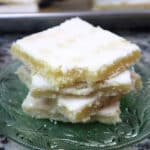 lemon bar slices stacked on a green glass plate.