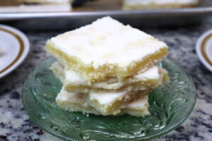 lemon bar slices stacked on a green glass plate.
