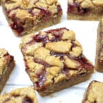 peanut butter jelly bars cut into squares on top of white parchment paper.