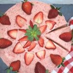 strawberry cake with slice cut from it and strawberries on top.