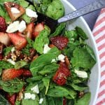spinach strawberry salad in a large white bowl.