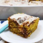 slice of pumpkin cinnamon roll cake on a white plate.