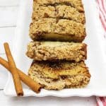Sliced Cinnamon Streusel Bread on a white dish with cinnamon sticks.