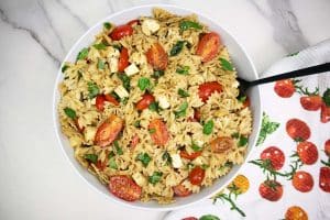Caprese pasta salad in a large white bowl.