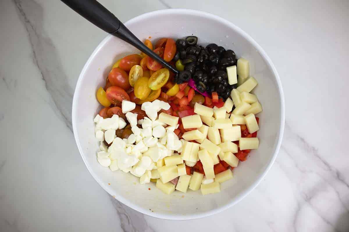 tortellini pasta salad ingredients mixed in a large white bowl.
