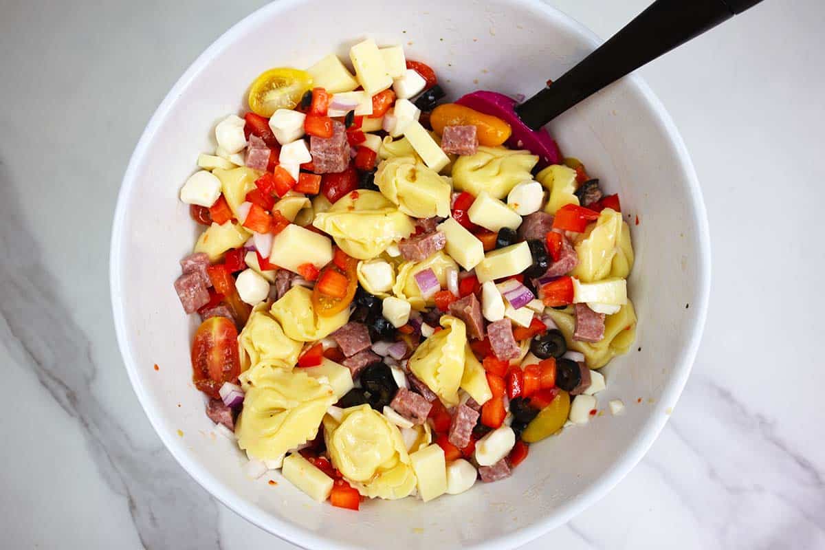tortellini pasta salad ingredients in a white bowl.