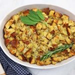 Cubed stuffing baked in a white dish with a blue and white towel on the side.