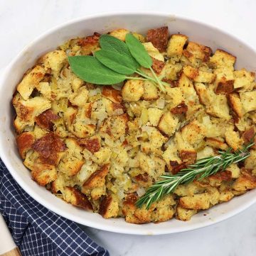 Cubed stuffing baked in a white dish with a blue and white towel on the side.