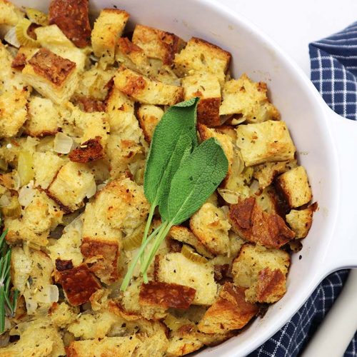 Cubed stuffing baked in a white dish with a blue and white towel on the side.