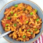 Taco mac and cheese served in a blue bowl with a silver spoon.