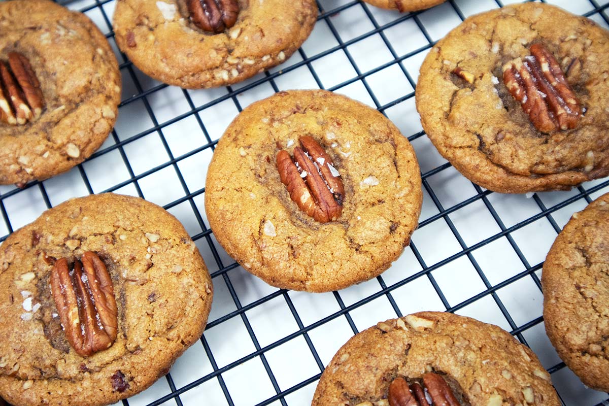 Butter pecan cookies on a black wire cooling rack.