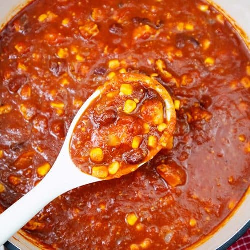Cooked chicken and corn chili in a large red pot.