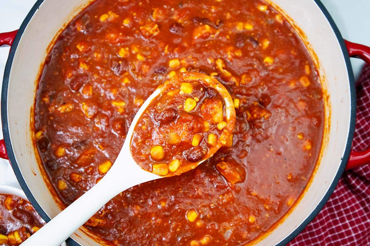 Cooked chicken and corn chili in a large red pot.