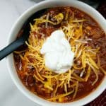 Chicken corn chili in a small white bowl with a black spoon.