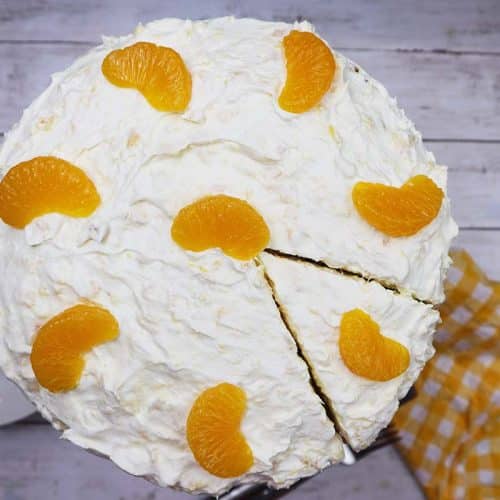 Pig Pickin Cake with mandarin oranges on top and a slice cut out.