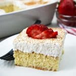 Tres Leche Cake slice with cinnamon and strawberries on top.