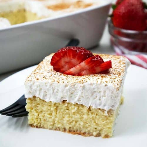 Tres Leche Cake slice with cinnamon and strawberries on top.